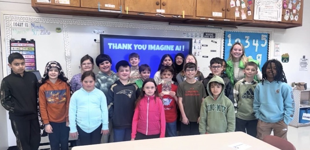 A teacher and her class gathered in front of a screen that reads Thank You Imagine AI.
