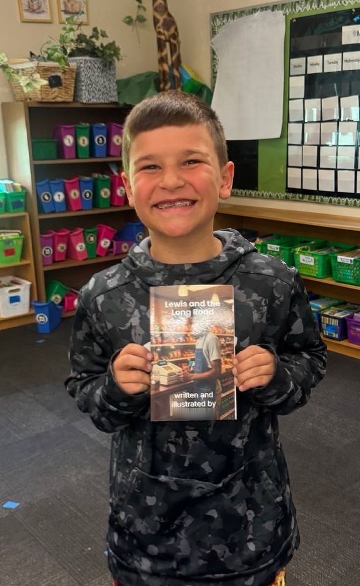 A young author proudly holding his printed book